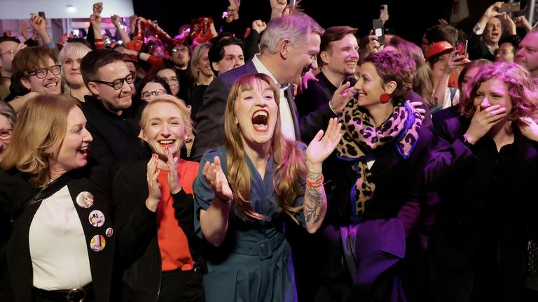 Heidi Reichinnek (Mitte), Spitzenkandidatin der Partei "Die Linke, reagiert zusammen mit den beiden Vorsitzenden Jan van Aken (Mitte) und Ines Schwerdtner (2-L) auf erste Ergebnisse während der Wahlveranstaltung in Berlin