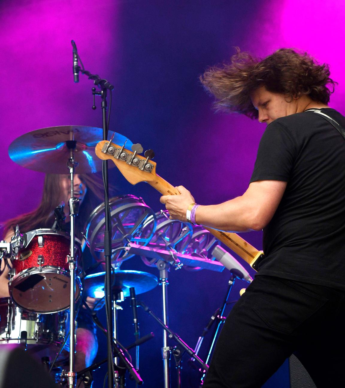 Auf einer lila angeleuchteten Bühne spielt ein Mann mit dem Rücken zum Publikum Gitarre, vor ihm sitzt ein Mann am Schlagzeug.