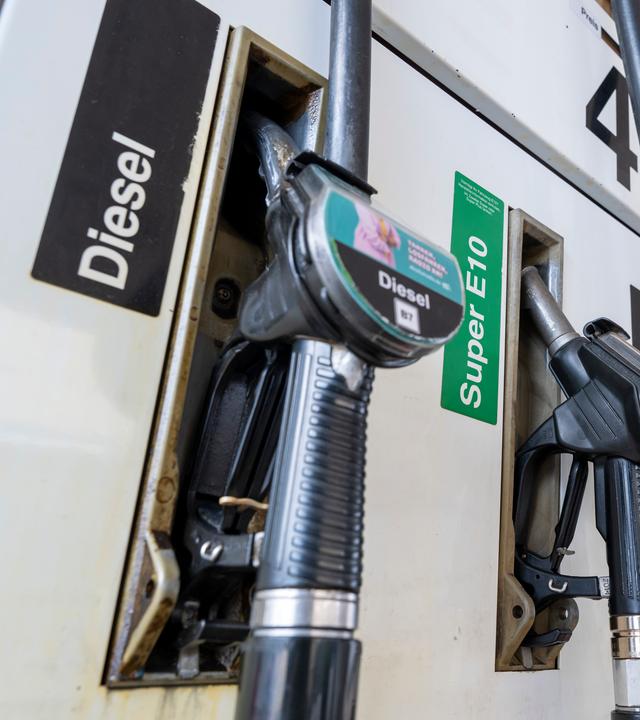 Zapfpistolen für Kraftstoff hängen an einer Tankstelle in der Halterung. 