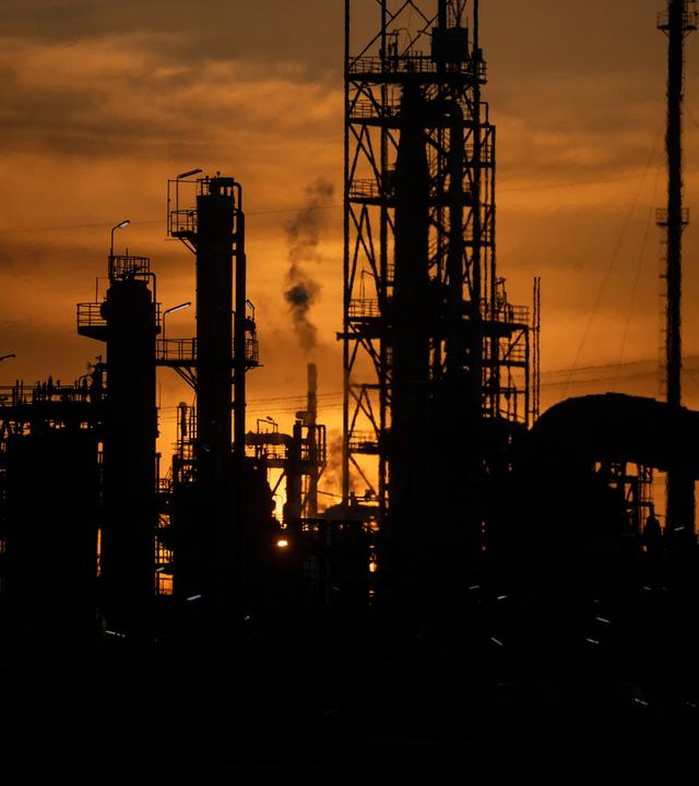 Industrieanlagen einer Mineralölraffinerie im Gegenlicht.