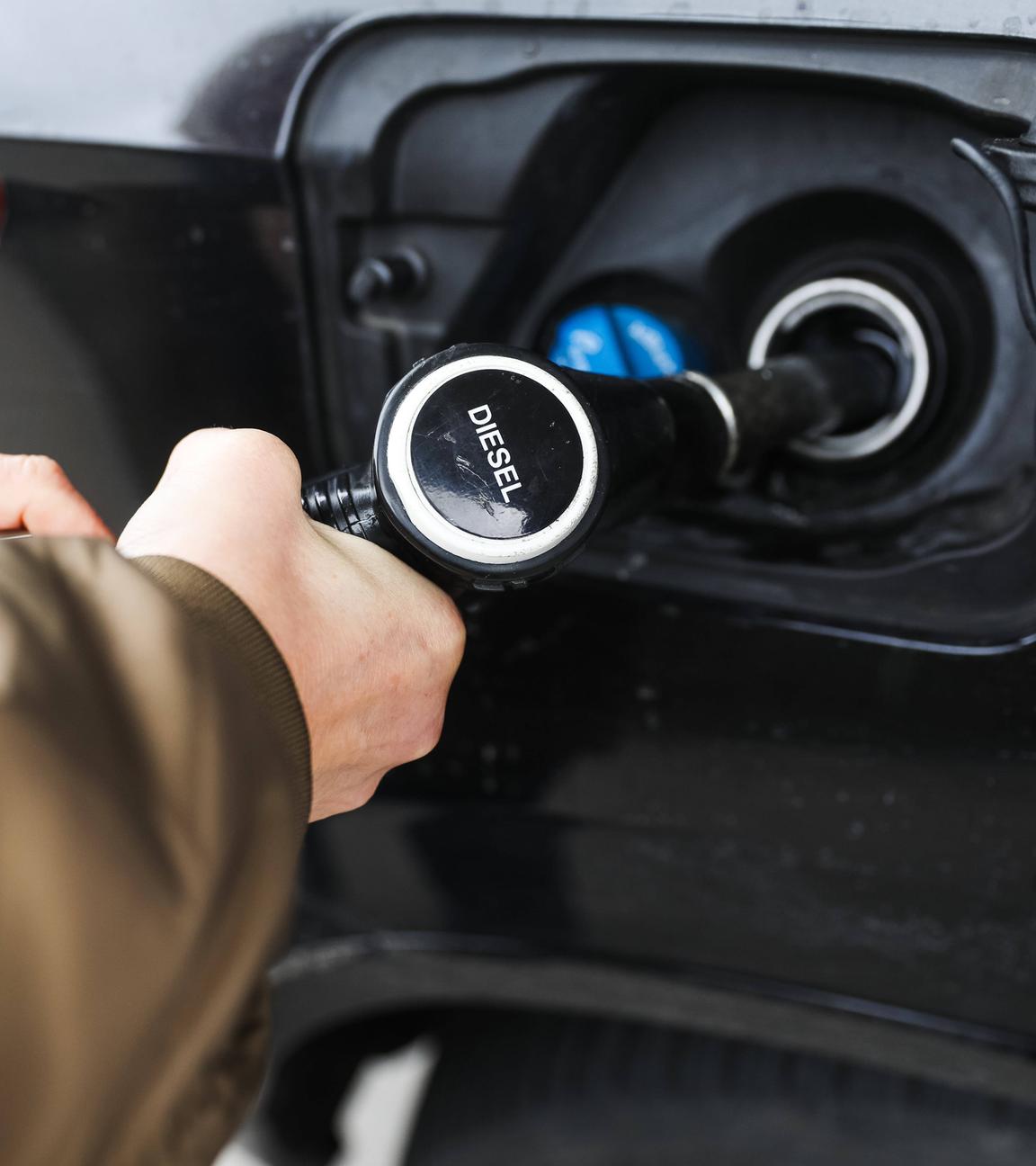 Frauenhände halten eine Diesel-Zapfpistole beim Betanken eines Fahrzeugs an einer Tankstelle.