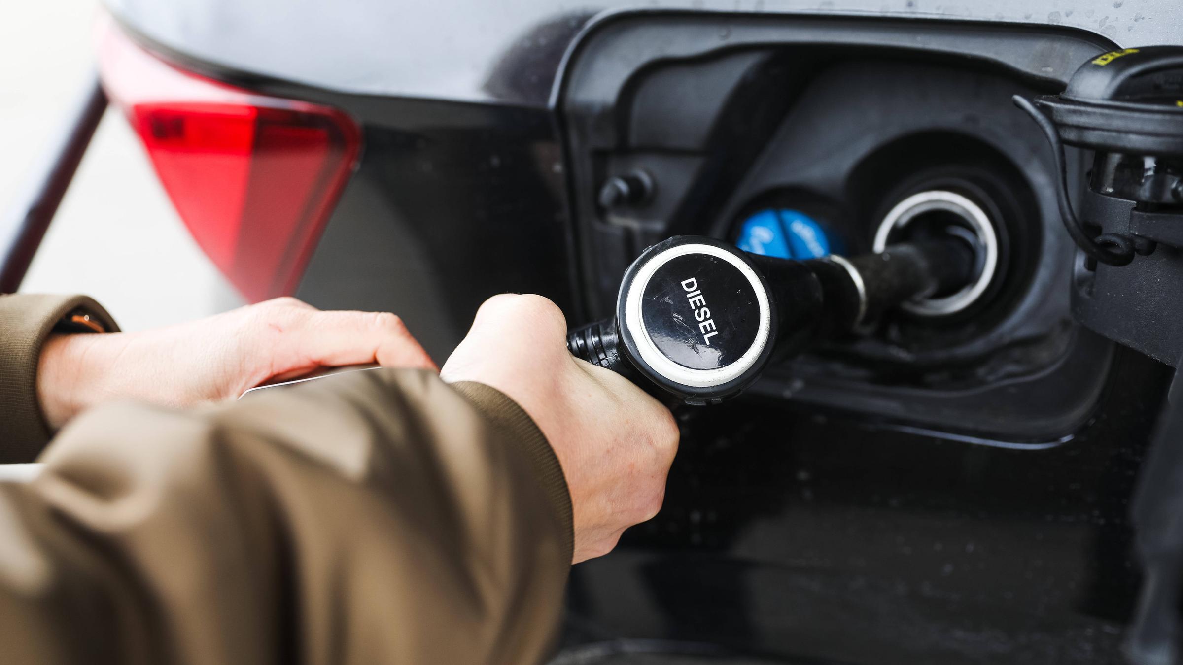 Frauenhände halten eine Diesel-Zapfpistole beim Betanken eines Fahrzeugs an einer Tankstelle.