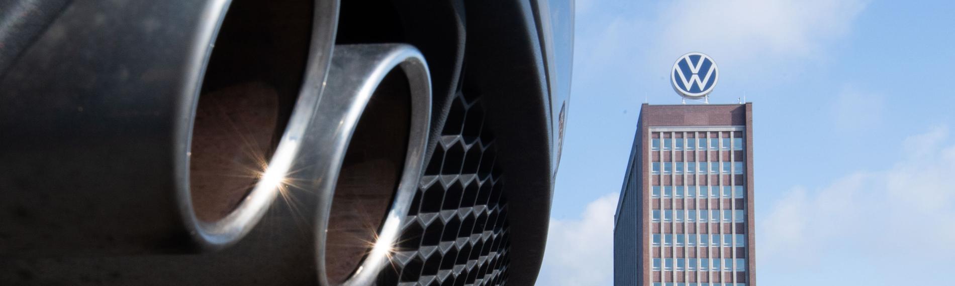 Auspuffrohre eines Volkswagen, fotografiert mit dem Markenhochhaus am VW-Werk Wolfsburg im Hintergrund. (Archiv)