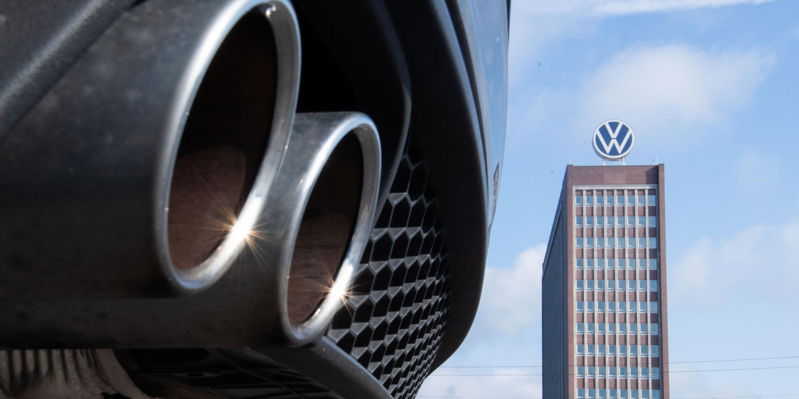 Auspuffrohre eines Volkswagen, fotografiert mit dem Markenhochhaus am VW-Werk Wolfsburg im Hintergrund. (Archiv)
