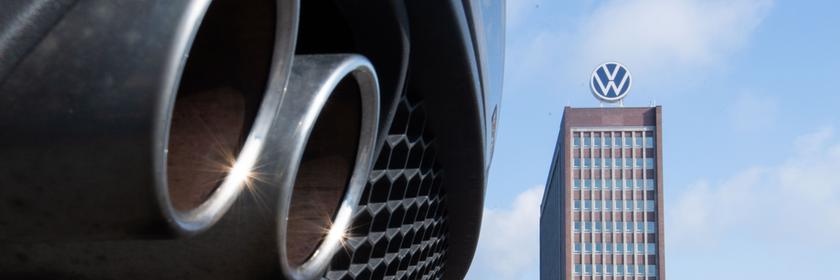 Auspuffrohre eines Volkswagen, fotografiert mit dem Markenhochhaus am VW-Werk Wolfsburg im Hintergrund. (Archiv)