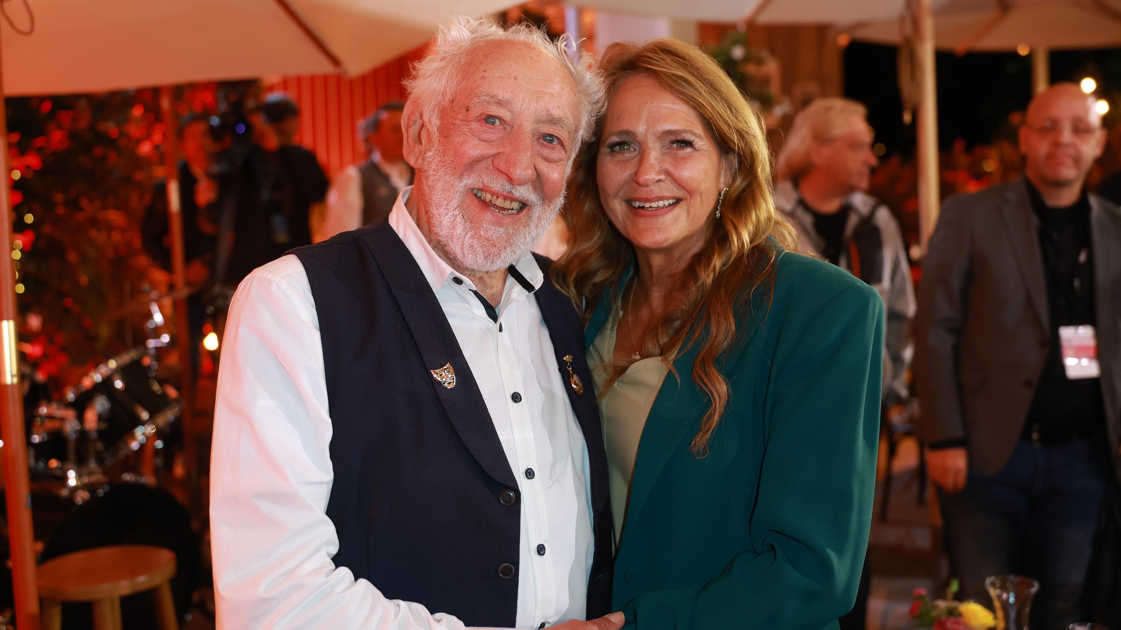 Dieter Hallervorden steht auf der linken Seite und seine Ehefrau Christiane Zander auf der rechten Seite. Sie lachen in die Kamera.