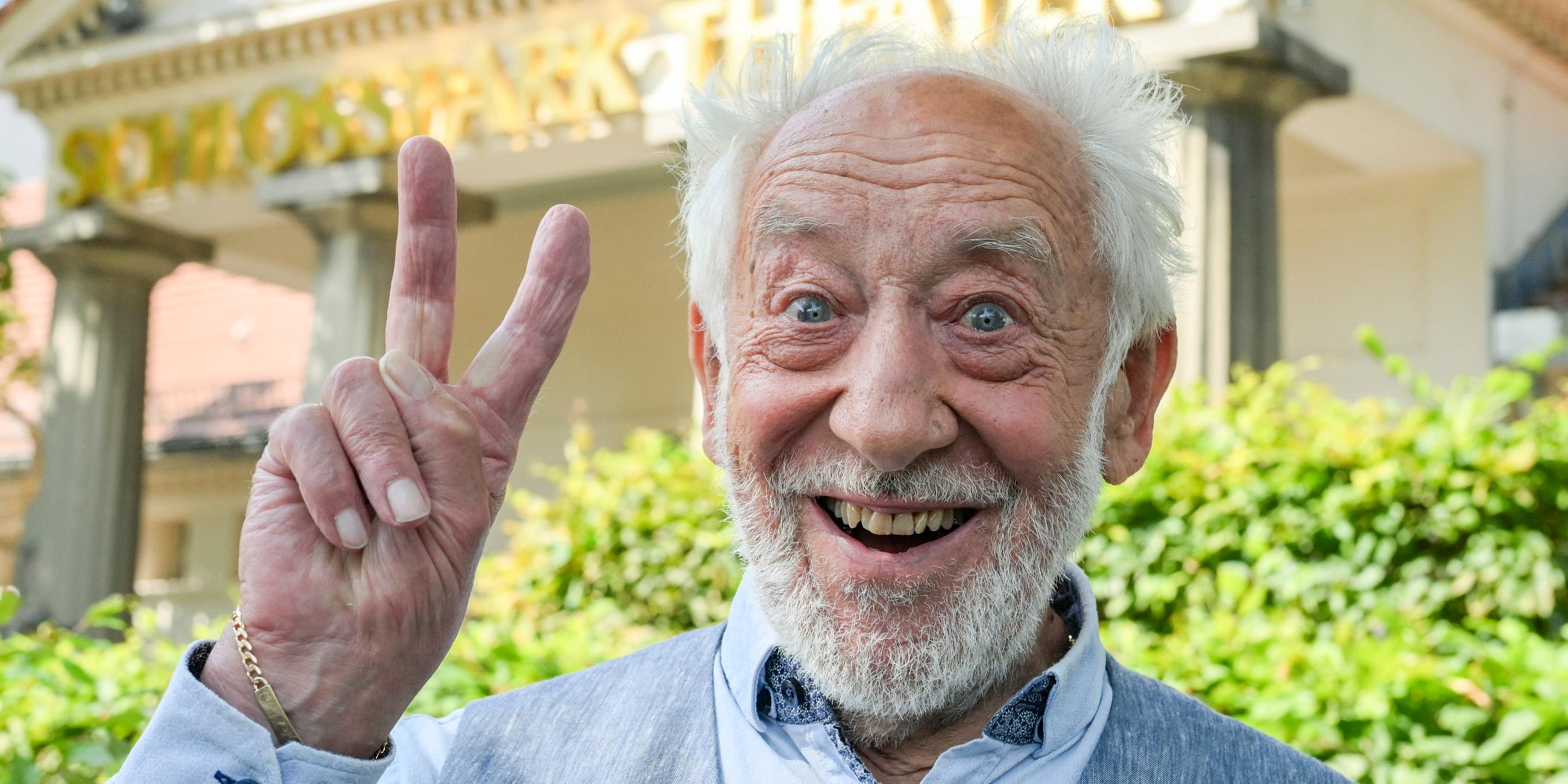 Dieter Hallervorden lächelt und macht ein Peace-Zeichen in die Kamera.