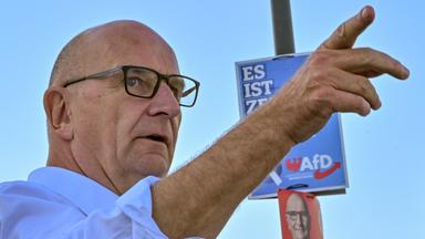 Dietmar Woidke (SPD), Ministerpräsident von Brandenburg, steht neben einem Wahlplakat der AfD.