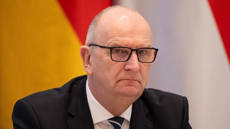 Dietmar Woidke mit ernstem Gesichtsausdruck vor einer Deutschlandfahne