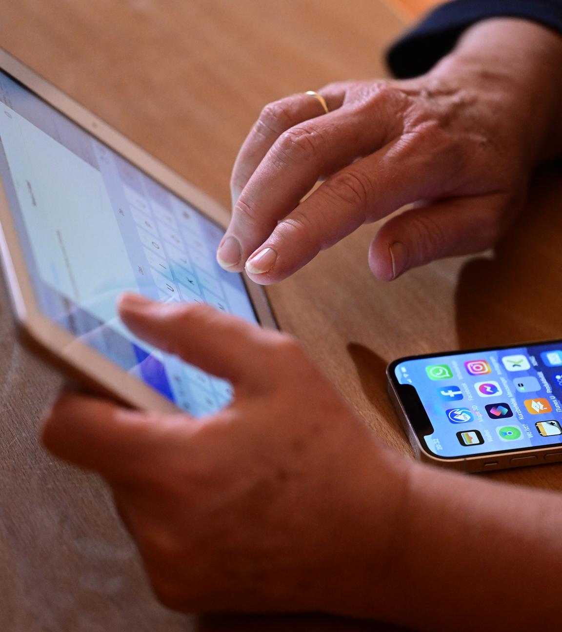 Ein Tablet wird bedient, darunter liegt ein Smartphone auf einem Tisch.