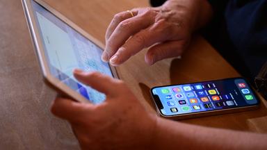 Ein Tablet wird bedient, darunter liegt ein Smartphone auf einem Tisch.