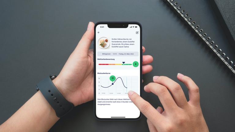 Eine Person hält ein Smartphone, auf dem eine Gesundheits-App geöffnet ist.
