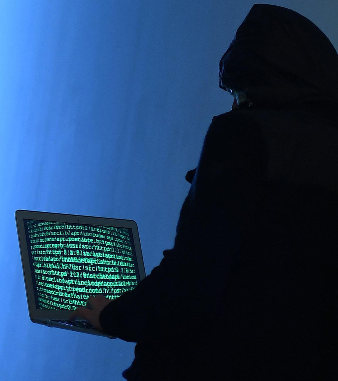 Ein Mann am Laptop versucht auf illegale Weise Passwörter und Seiten im Internet zu hacken.