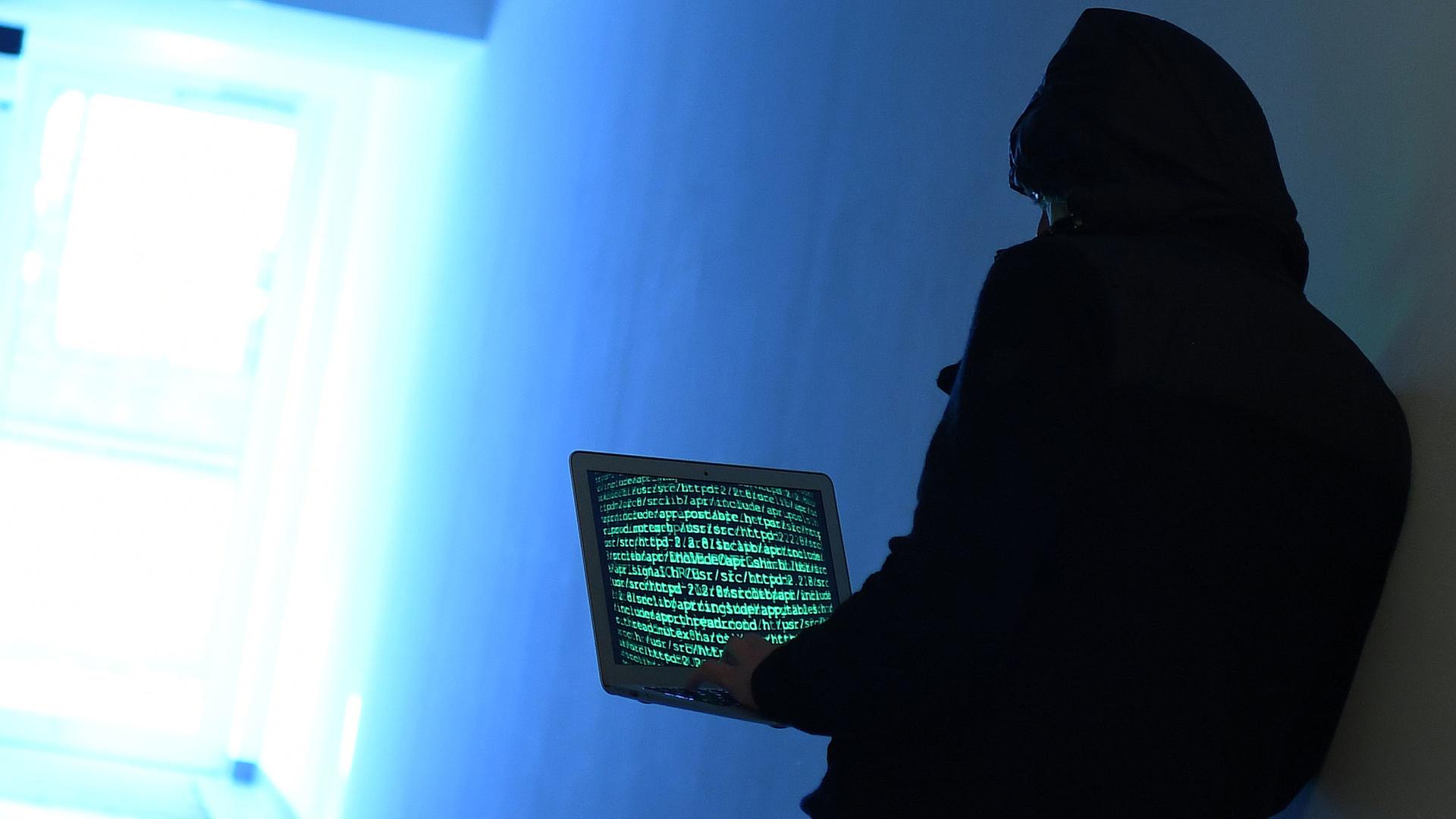 Ein Mann am Laptop versucht auf illegale Weise Passwörter und Seiten im Internet zu hacken.