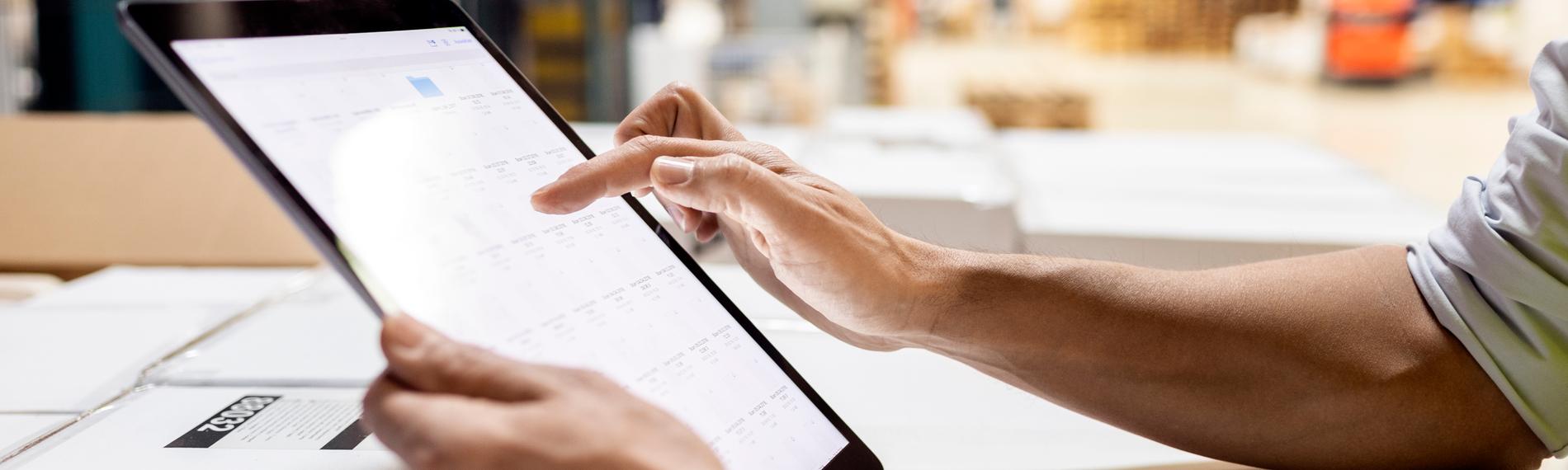 Hände eines Arbeiters, der einen Tablet-PC zur Überprüfung des Inventars im Lager benutzt