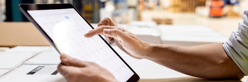 Hände eines Arbeiters, der einen Tablet-PC zur Überprüfung des Inventars im Lager benutzt