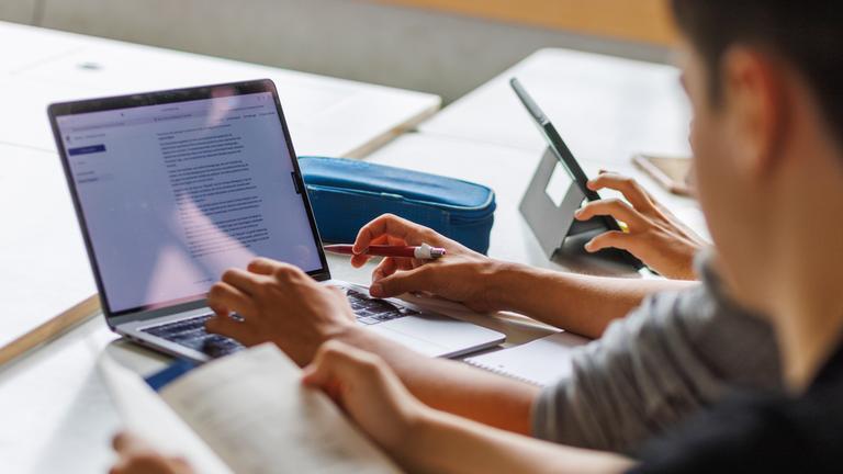 Schüler eines Gymnasiums sitzen vor einem Computer und benutzen ein KI-Tool