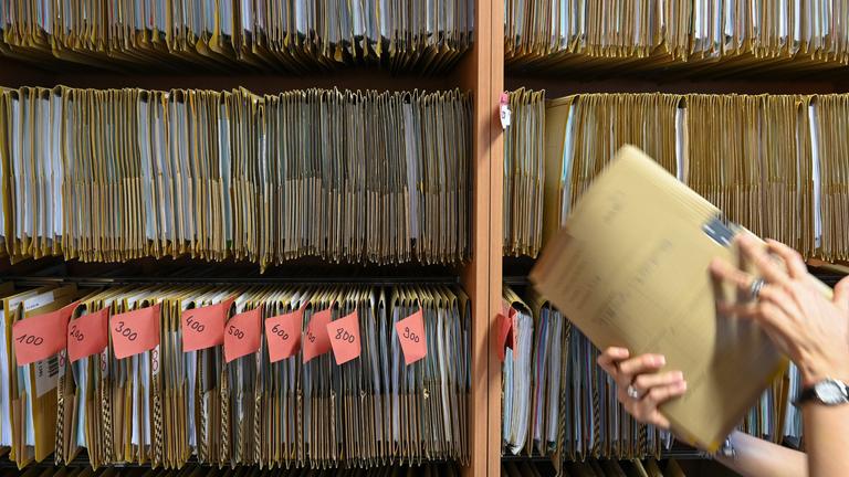 Frankfurt/Main: Eine Mitarbeiterin einer Behörde greift an einem Regal nach einer Akte.