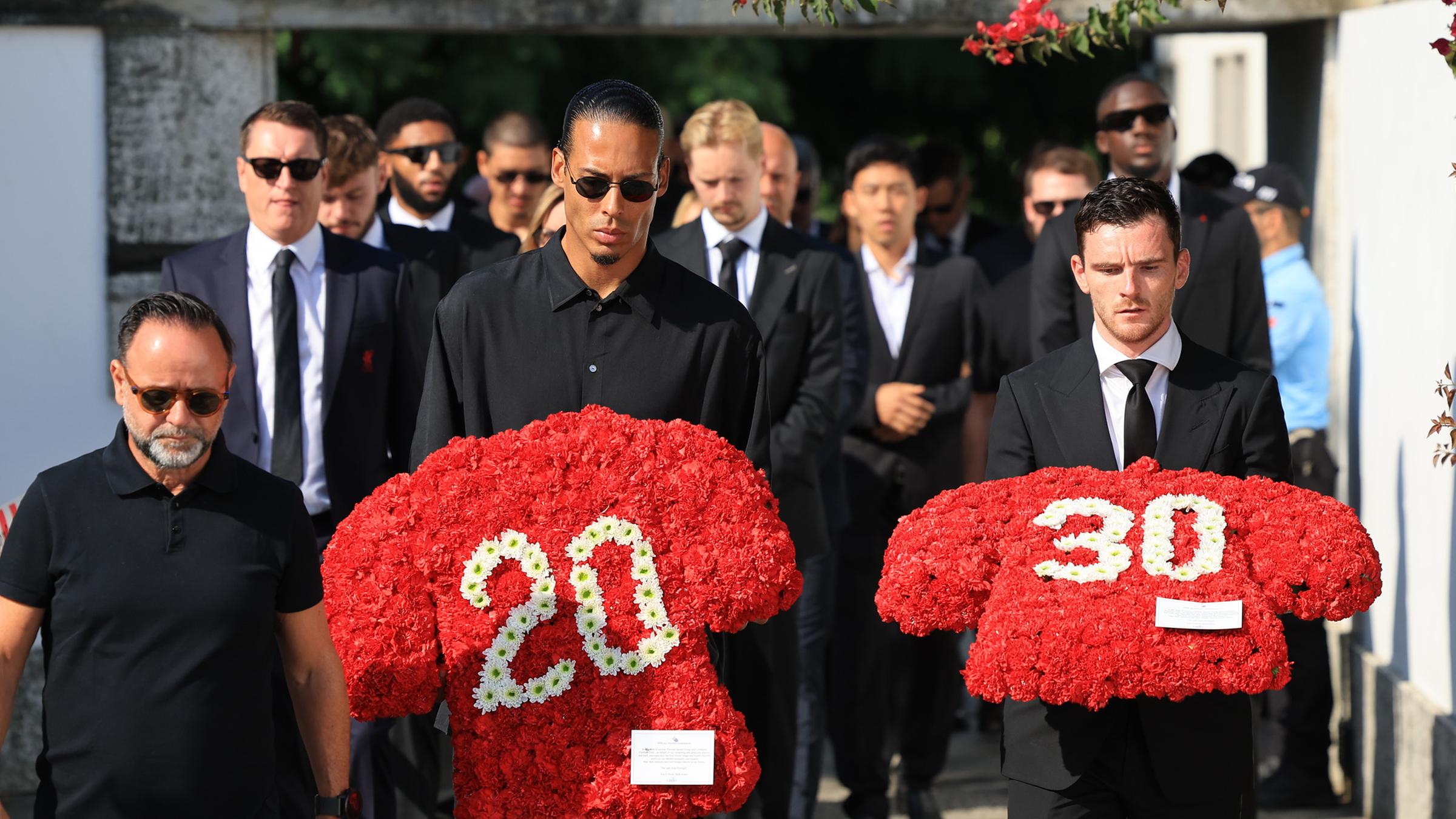 Die Liverpoolspieler Virgil van Dijk (Mitte) und Andrew Robertson (Rechts) tragen einen Blumenkranz mit der Spielernummern von Diogo Jota und Andre Silva während der Beerdigung von Diogo Jota in Gondomar, Portugal.