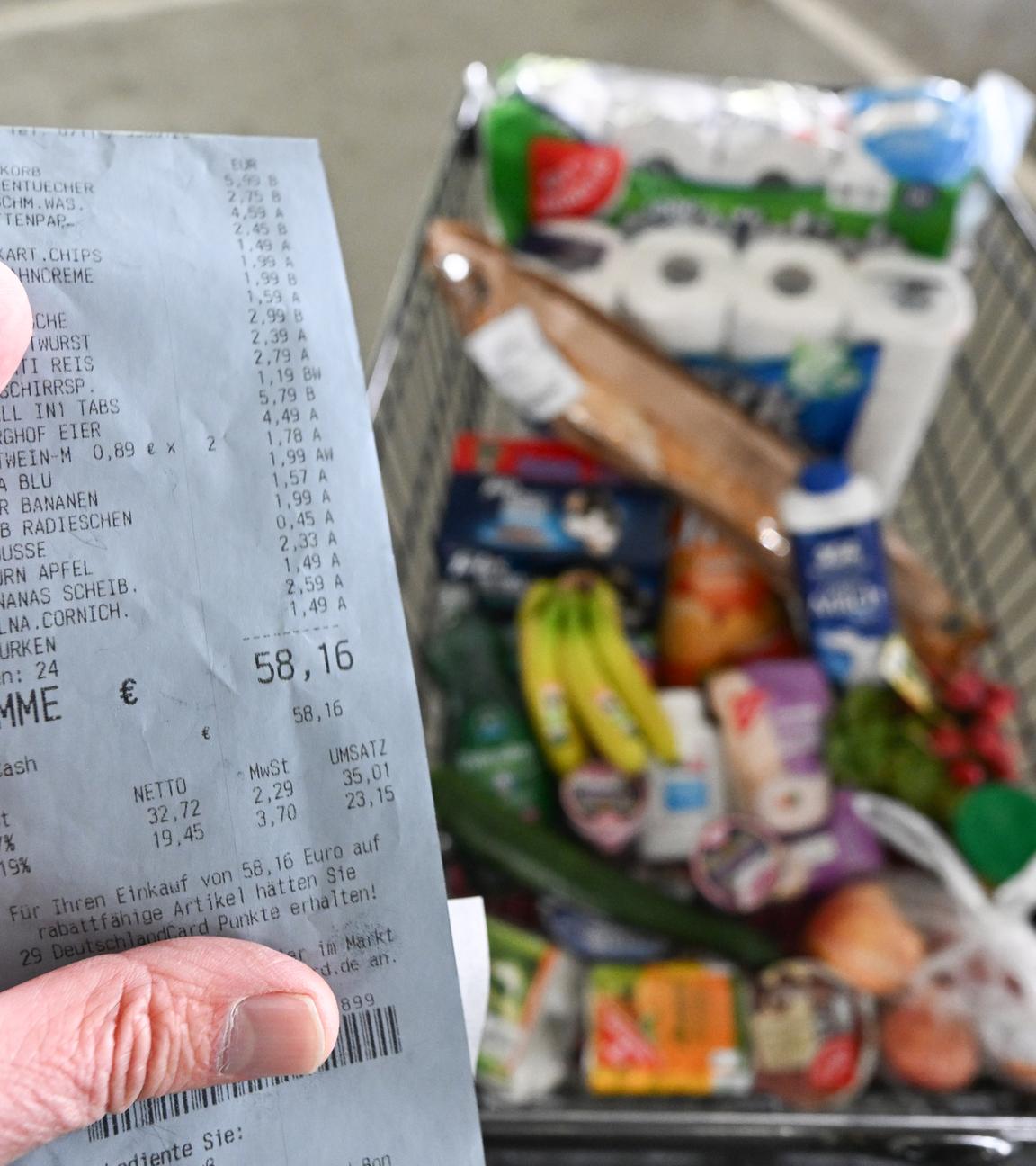 Ein Verbraucher hält nach einem Einkauf in einem Supermarkt einen Kassenzettel in der Hand. 