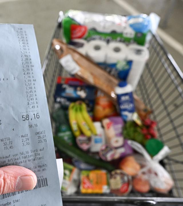 11.04.2024, Baden-Württemberg, Eßlingen: Ein Verbraucher hält nach einem Einkauf in einem Supermarkt einen Kassenzettel in der Hand.