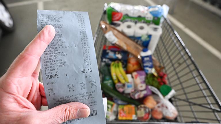 11.04.2024, Baden-Württemberg, Eßlingen: Ein Verbraucher hält nach einem Einkauf in einem Supermarkt einen Kassenzettel in der Hand.