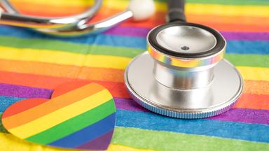 Zu sehen ist ein Stethoskop auf einer Regenbogenflagge.