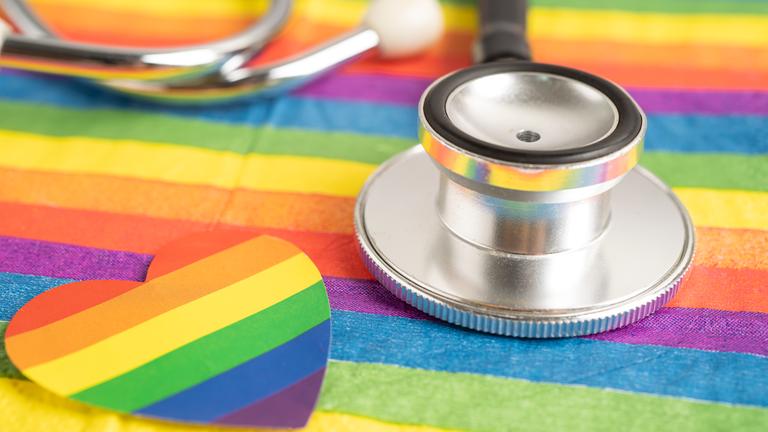 Zu sehen ist ein Stethoskop auf einer Regenbogenflagge.