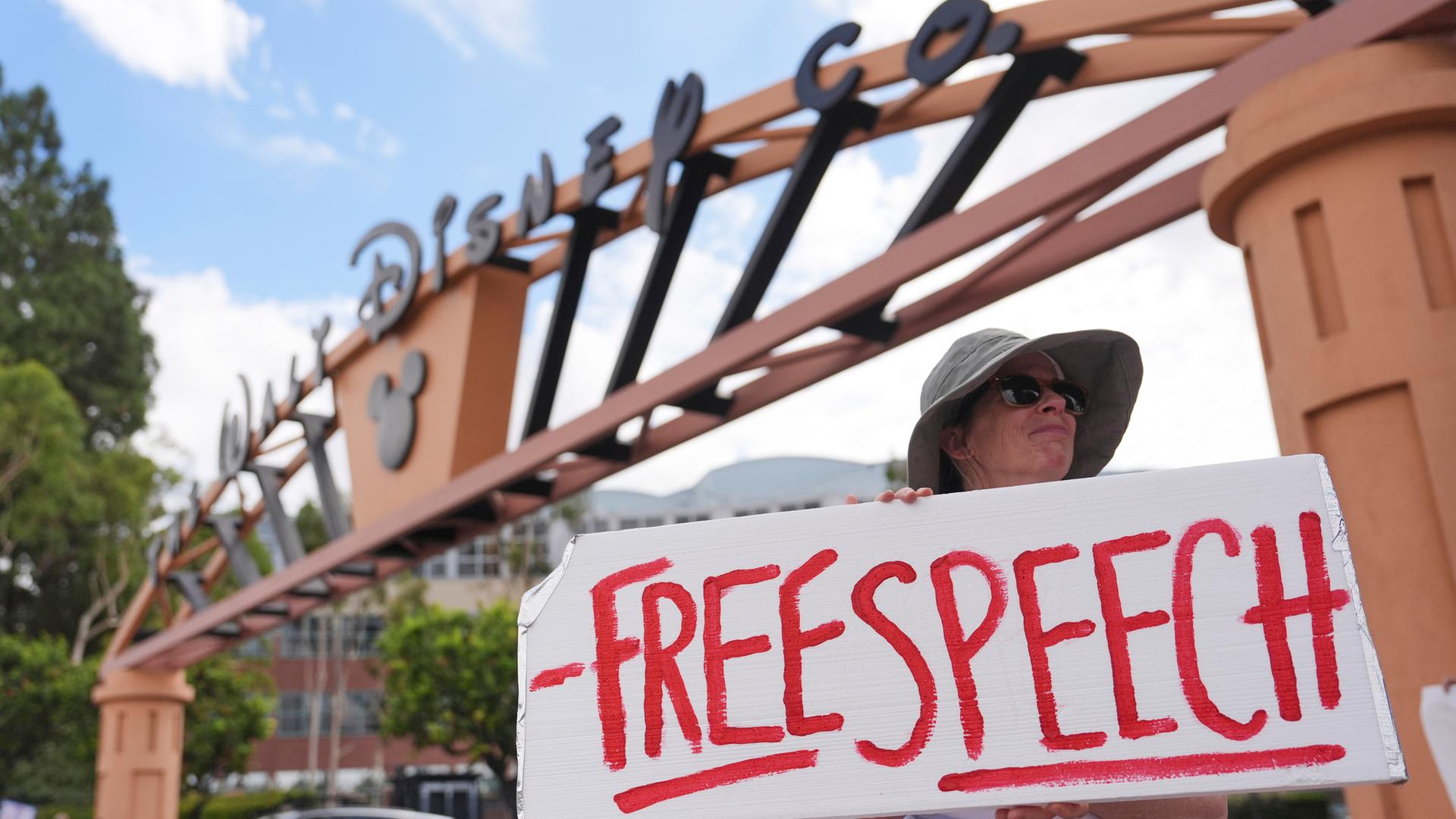 Eine Demonstrantin steht vor den Walt Disney Studios und hält ein Schild mit der Aufschrift "Meinungsfreiheit".