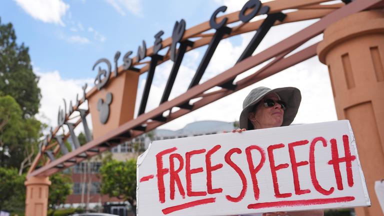 Eine Demonstrantin steht vor den Walt Disney Studios und hält ein Schild mit der Aufschrift "Meinungsfreiheit".