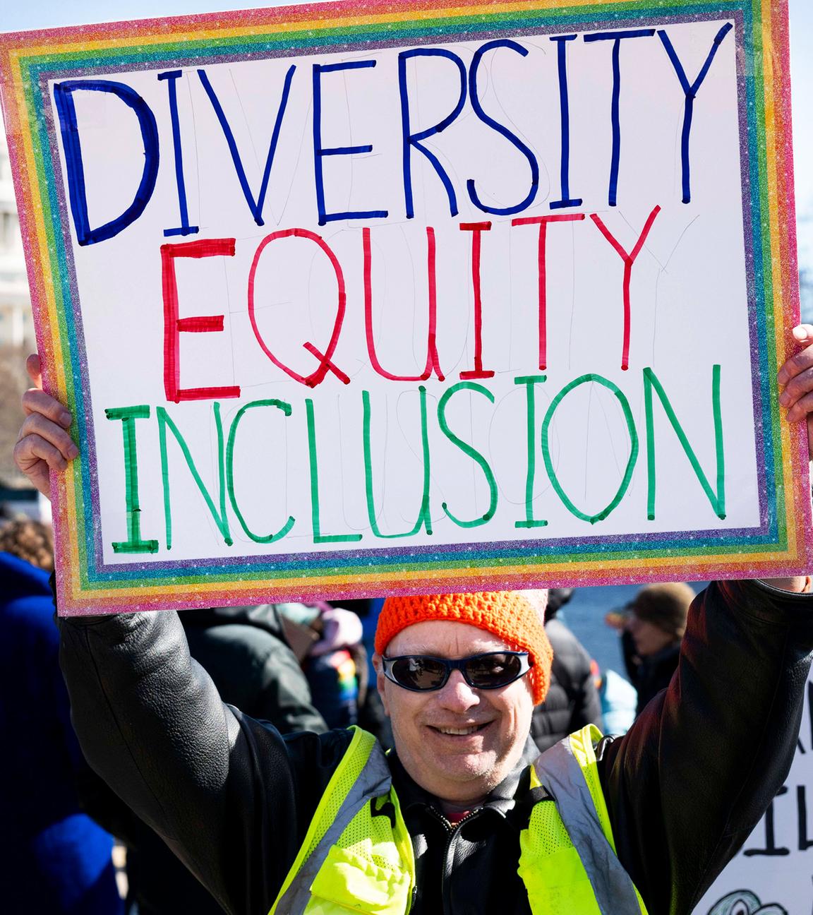 Ein Demonstrant hält ein Schild mit der Aufschrift "Diversity, Equity, Inclusion" hoch. Im Hintergund ist das Capitol in Washington zu sehen.