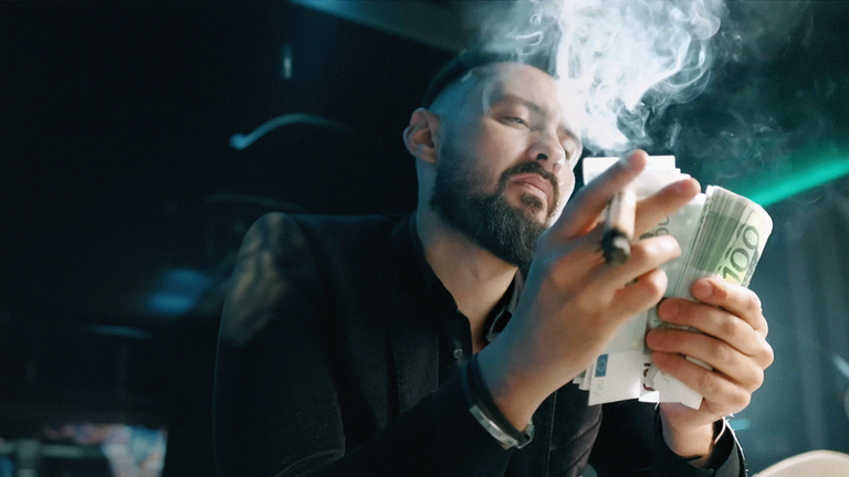 Zigarre rauchender Mann zählt Geldscheine 