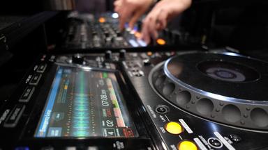 Ein DJ spielt in einer Halle der Leipziger Messe.