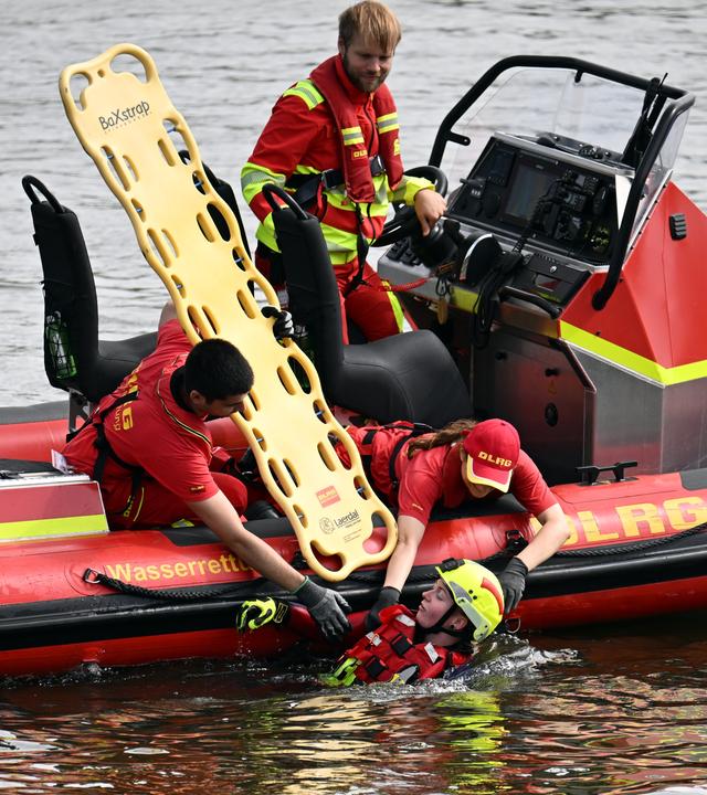 Rettungsschwimmer der Deutschen Lebens-Rettungs-Gesellschaft (DLRG) demonstrieren die Rettung einer Person aus dem Rhein.