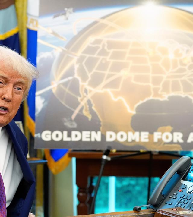 Links Donald Trump, der mit einem Plakat das Raketenabwehrsystem "Golden Dome" vorstellt. Auf dem Plakat ist die USA gold markiert, über den USA ist ein goldener Schirm, der Raketen abhält