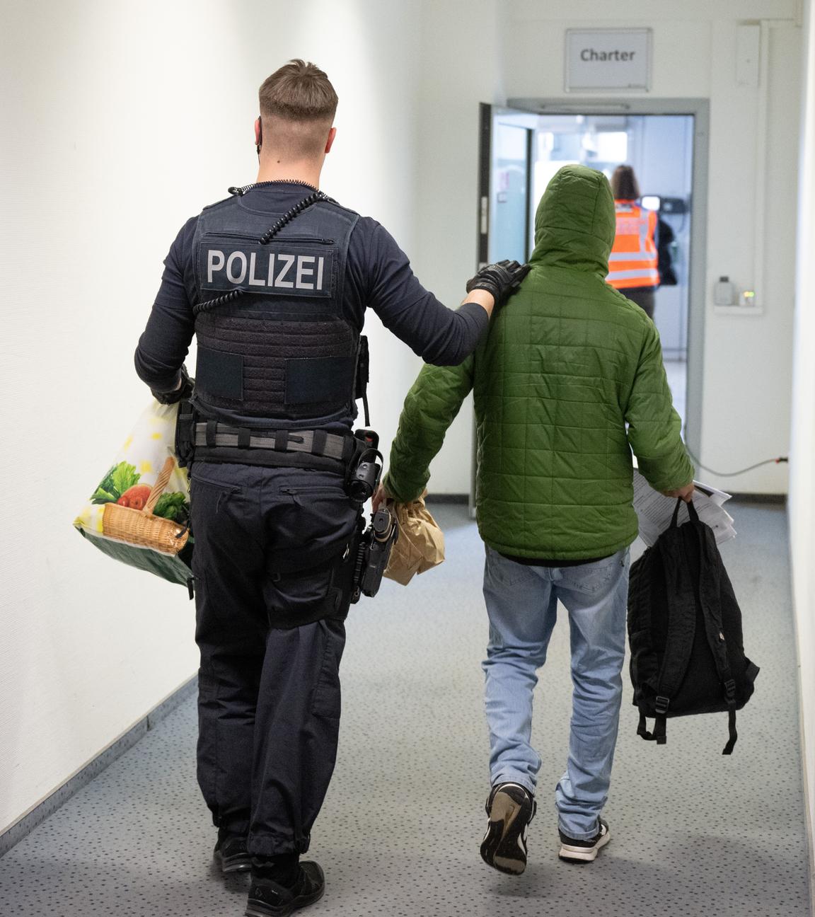 Ein Polizeibeamter bringt einen Mann zu einem Abschiebeflug nach Pakistan.