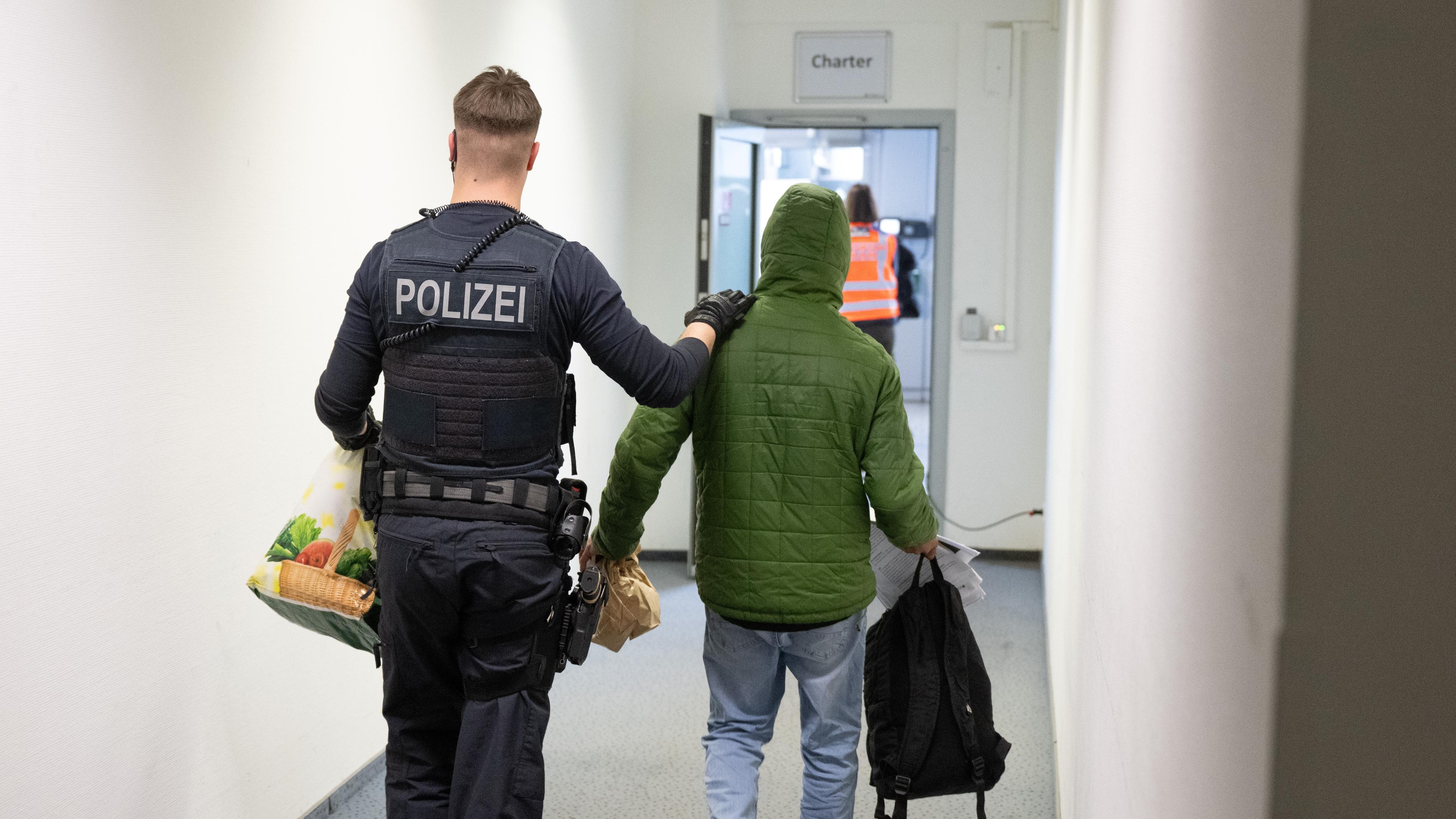 Ein Polizeibeamter bringt einen Mann zu einem Abschiebeflug nach Pakistan.
