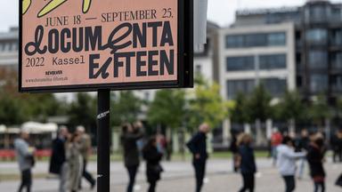 Besucher stehen hinter einem Veranstaltungsplakat am Eingang zum Museum Fridericianum in einer Schlange.