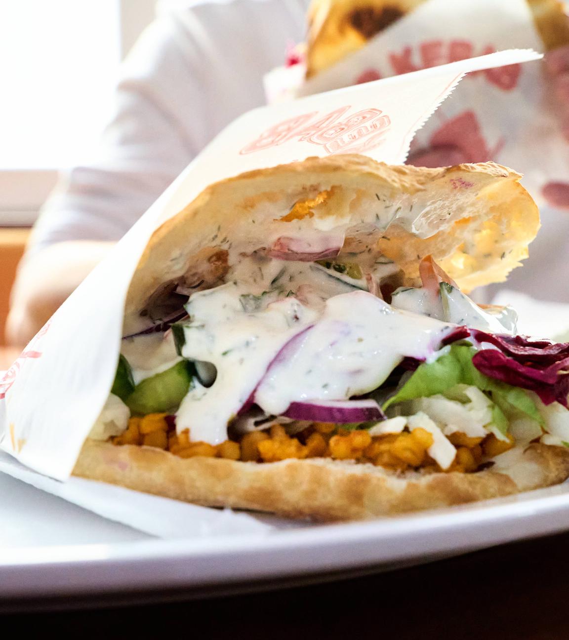 Auf einem weißen Teller ein Döner im Fladenbrot: mit Rotkraut, weißer Soße und Salat.