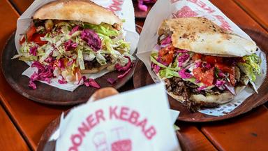 Auf einem Tisch liegen drei Portionen Döner Kebap mit Fleisch, Salat und Sauce.