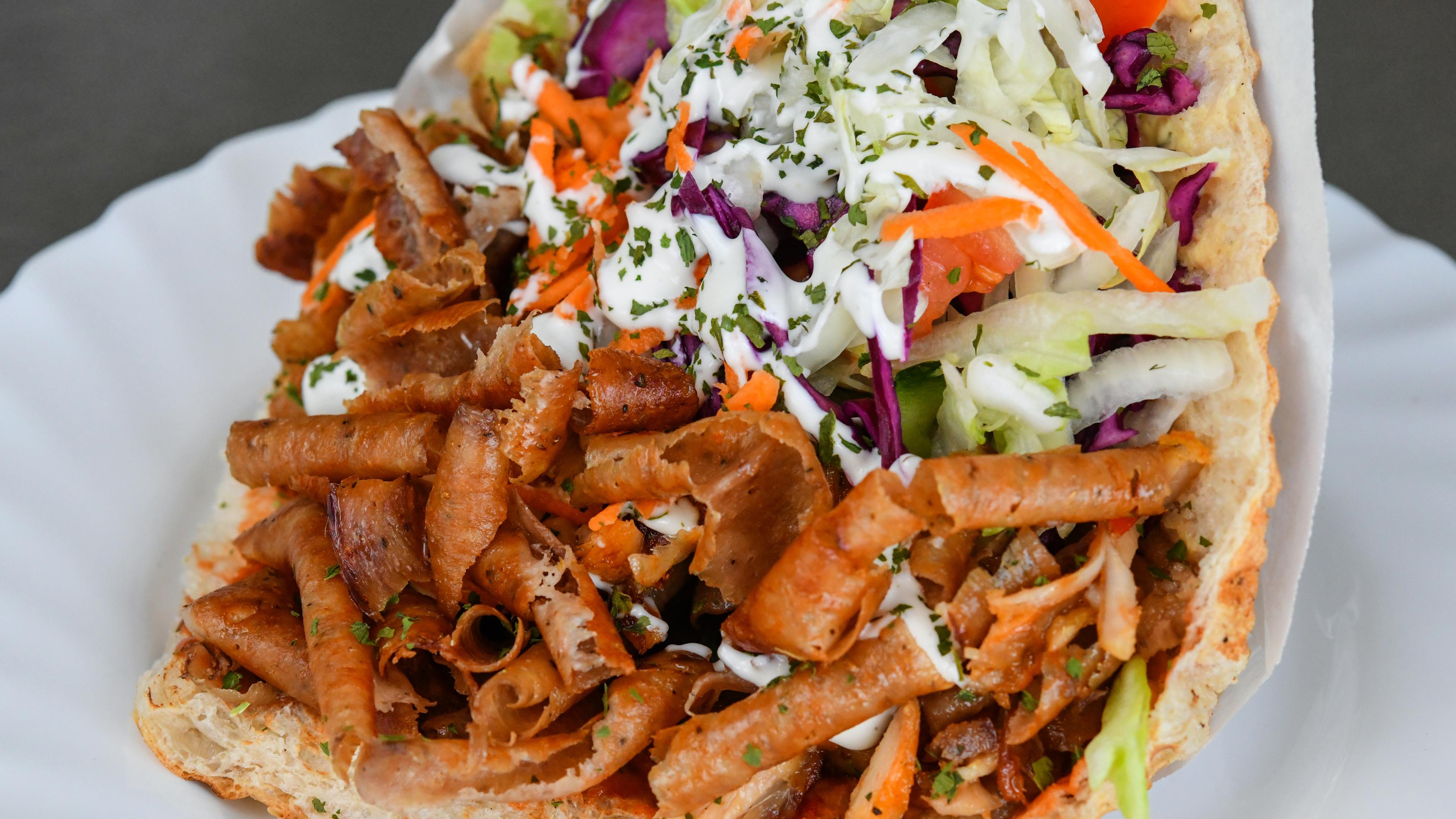 Ein großer Döner gefüllt mit Fleisch, Salat, Gemüse und Soße. 