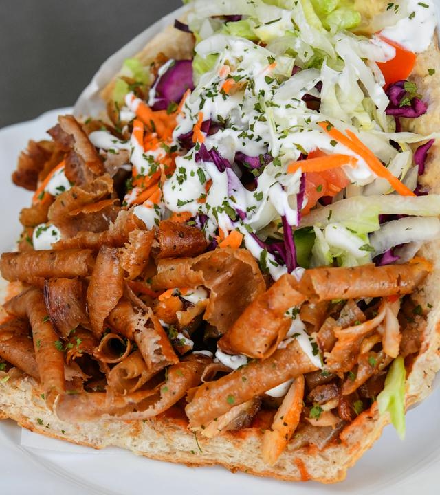 Ein großer Döner gefüllt mit Fleisch, Salat, Gemüse und Soße. 