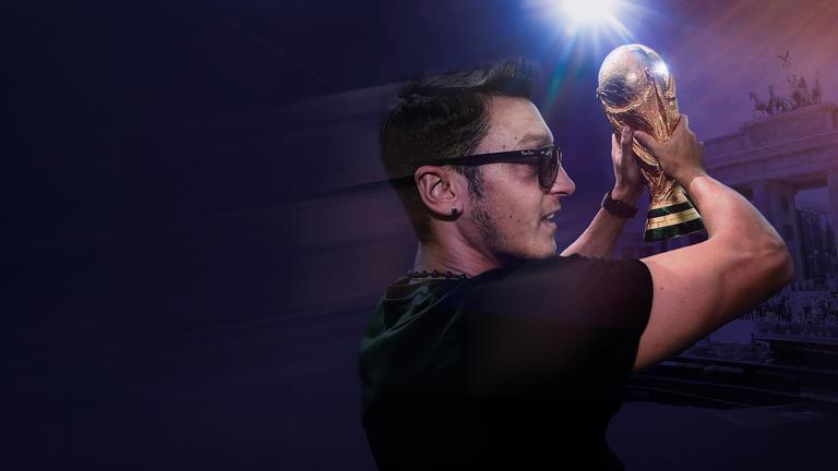 Collage: Mesut Özil hält einen Fußball-Pokal in die Höhe, rechts von ihm das Brandenburger Tor.