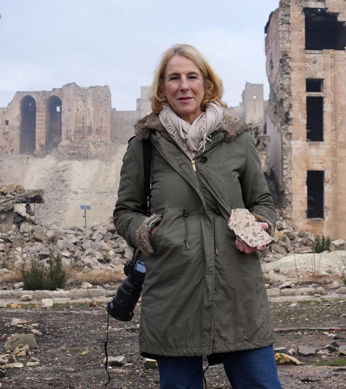 Katrin Eigendorf im der kriegsversehrten Altstadt von Aleppo, Syrien, in der Hand ein Stück Mauer.