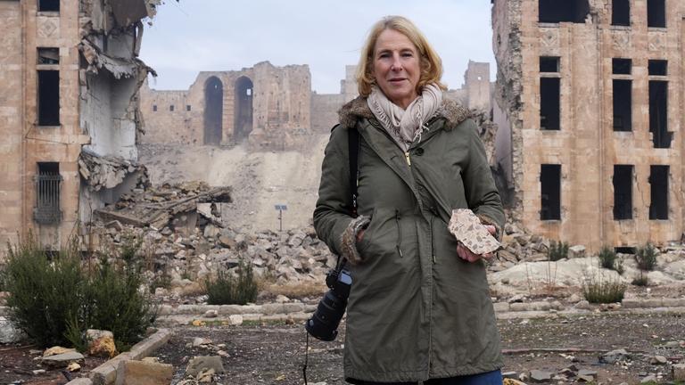 Katrin Eigendorf im der kriegsversehrten Altstadt von Aleppo, Syrien, in der Hand ein Stück Mauer.