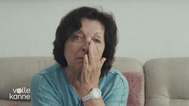 Eine Frau hält die Hand unter den Augen, kämpft mit Tränen.