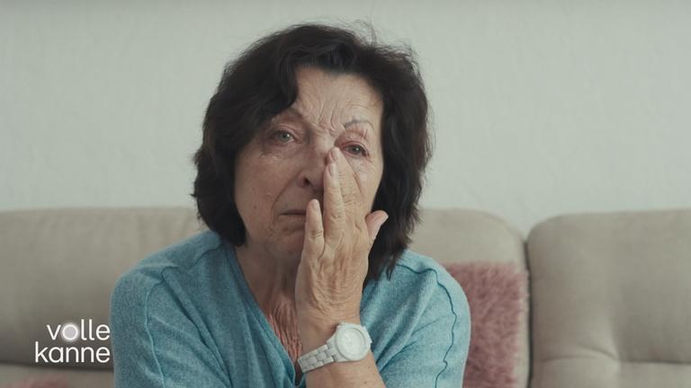 Eine Frau hält die Hand unter den Augen, kämpft mit Tränen.