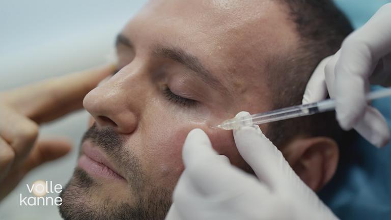 Einem Mann wird eine Flüssigkeit ins Gesicht gespritzt.