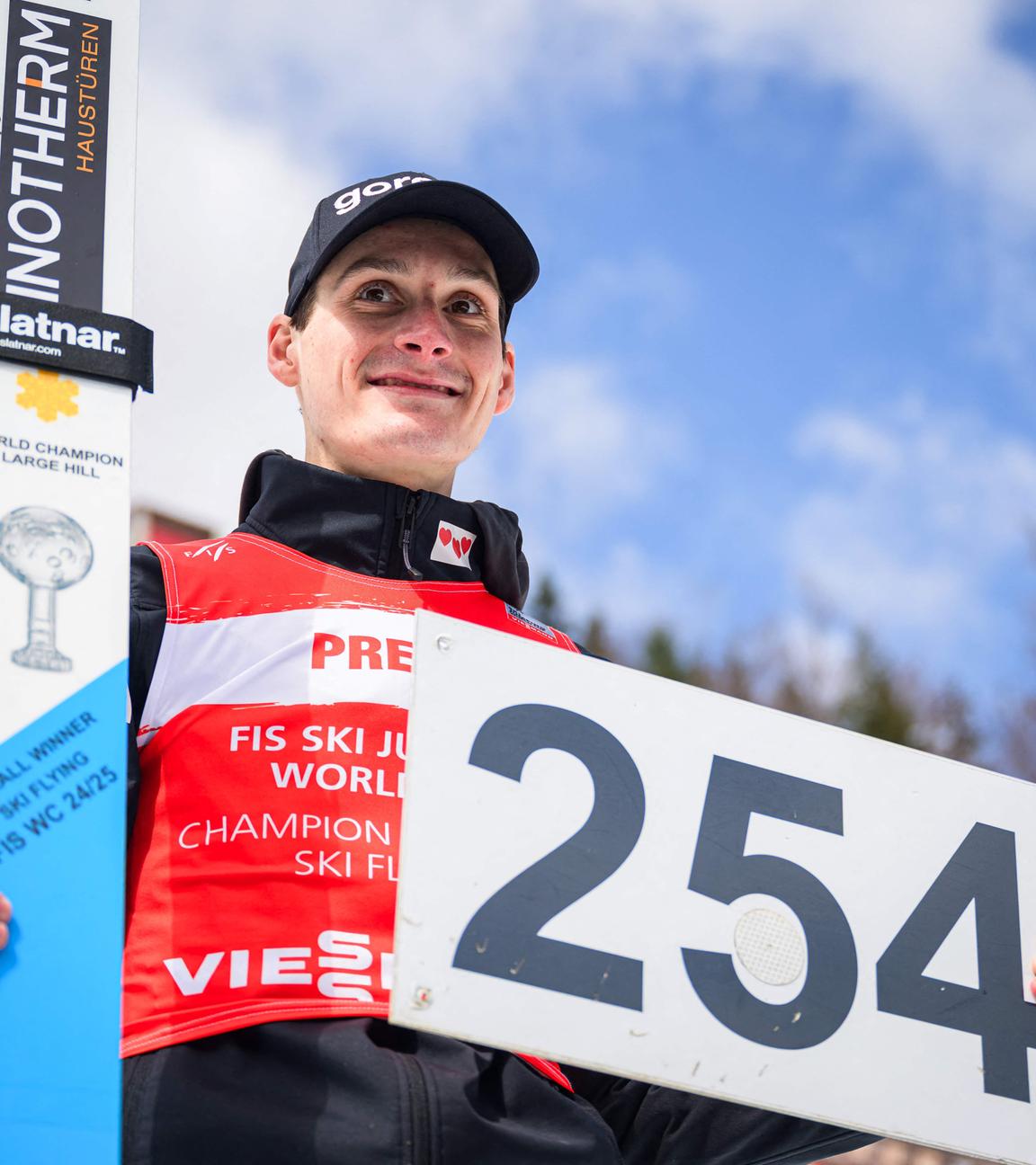 Domen Prevc zeigt ein Schild mit der neuen Weltrekordweite von 254 Metern in die Kamera.
