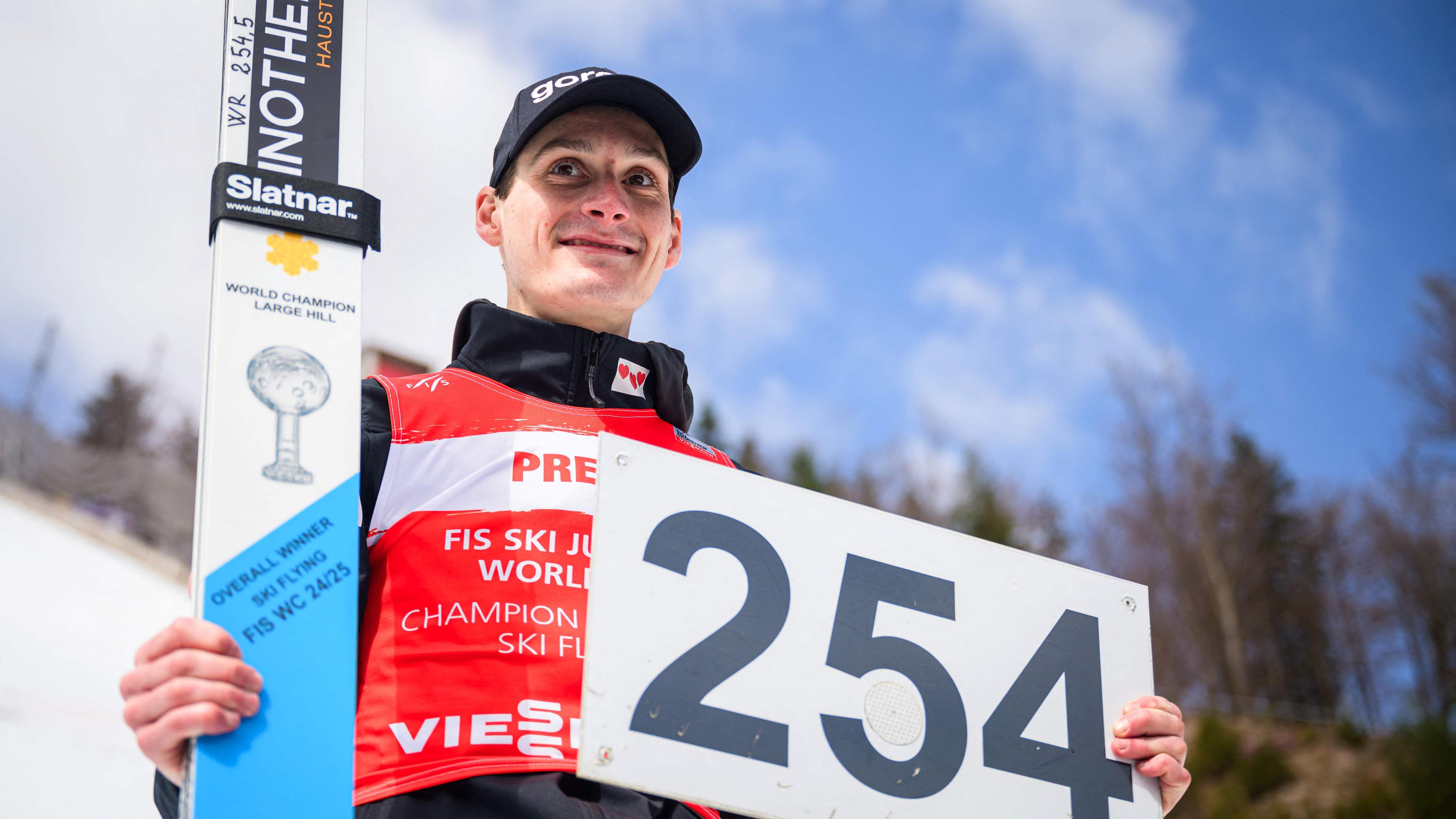 Domen Prevc zeigt ein Schild mit der neuen Weltrekordweite von 254 Metern in die Kamera.
